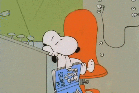 snoopy asleep in an orange chair holding an open book